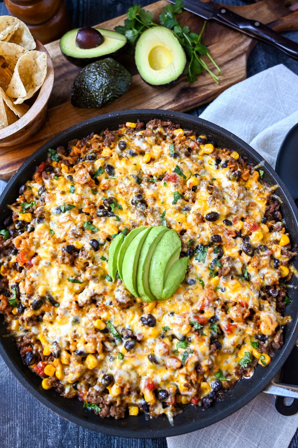 overhead shot of a skillet with a taco rice one dish dinner with slice avocado on top