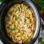 a zoomed in photo of green chili chicken in a crockpot with fresh cilantro on top