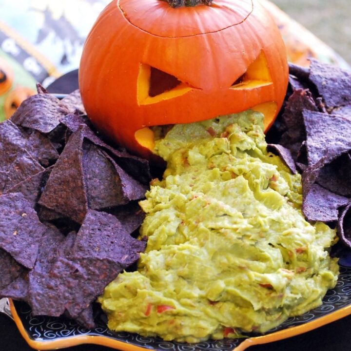 a pumpkin with guacamole trailing out of the carved mouth