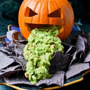 a vomiting pie pumpkin with guacamole coming out of it's mouth on a Halloween platter