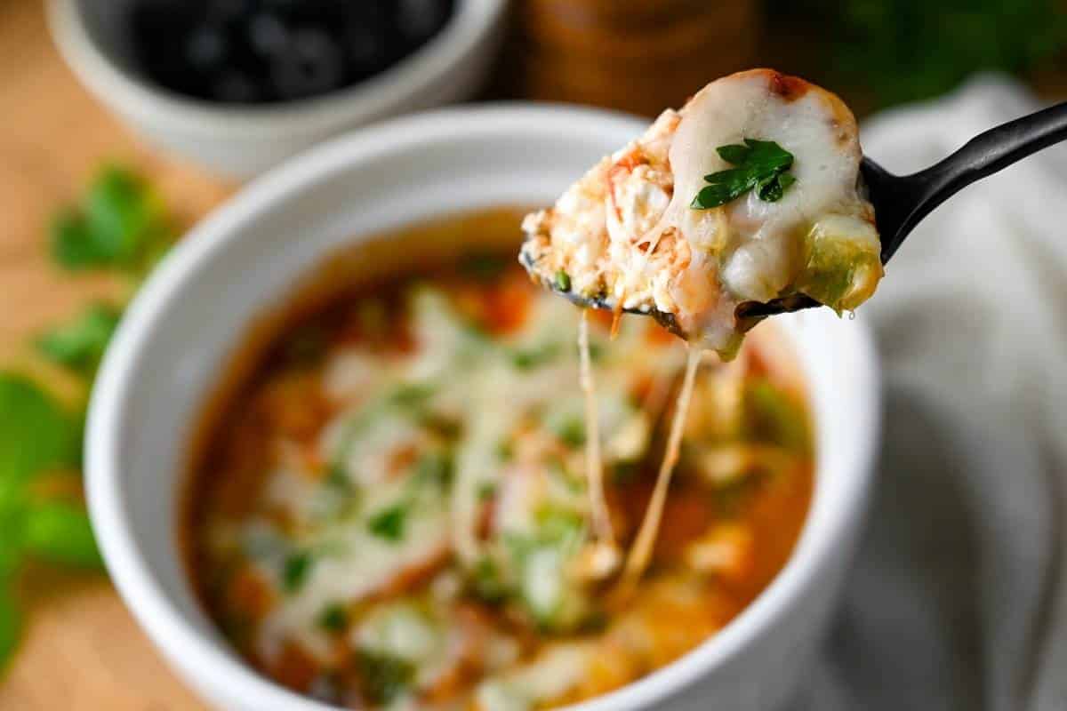 holding up a cheesy bite of a low carb pizza bowl made with cottage cheese