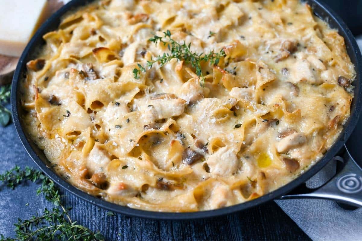 a skillet with baked chicken casserole with egg noodles and fresh herbs