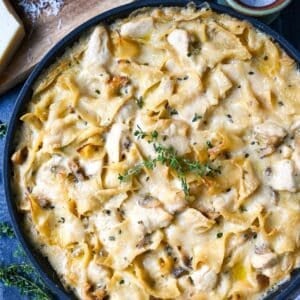 looking down at a skillet of chicken noodle casserole with a sprig of thyme on top