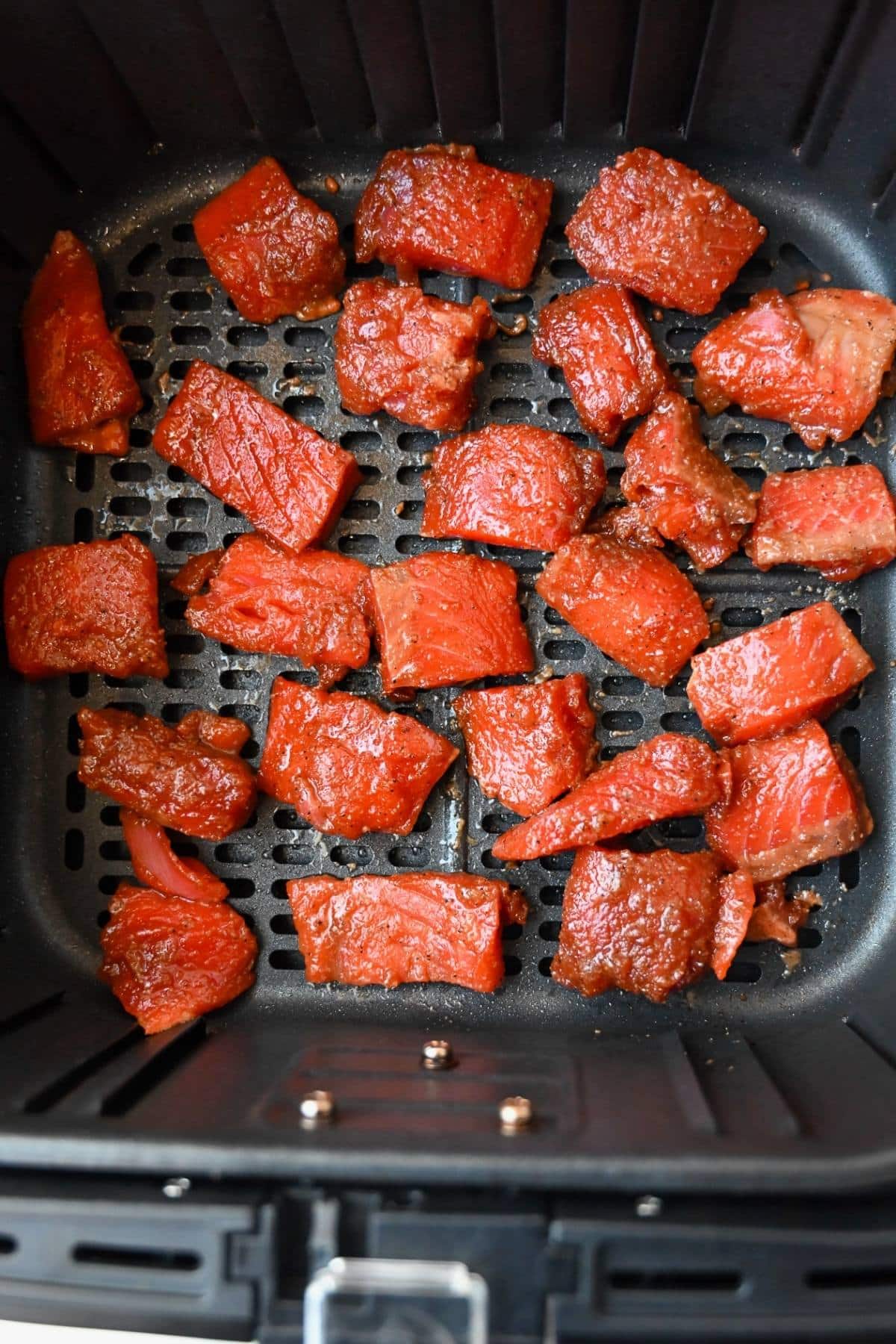 cubed and marinated wild salmon cut into bite size pieces in an air fryer basket