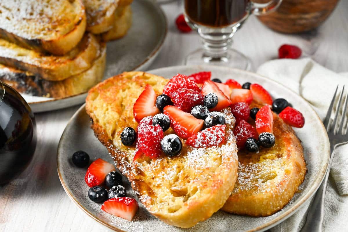 sliced french toast with a bottle of maple syrup and a cup of coffee