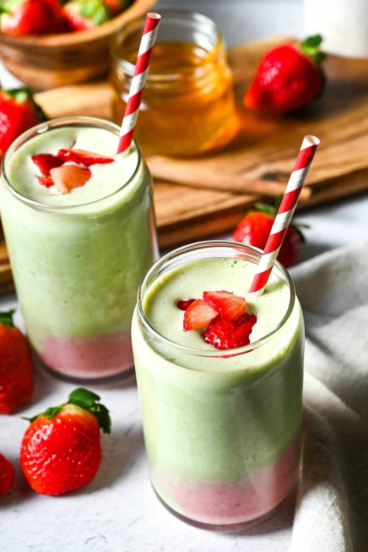 two ombre strawberry matcha smoothies with sliced fresh strawberries