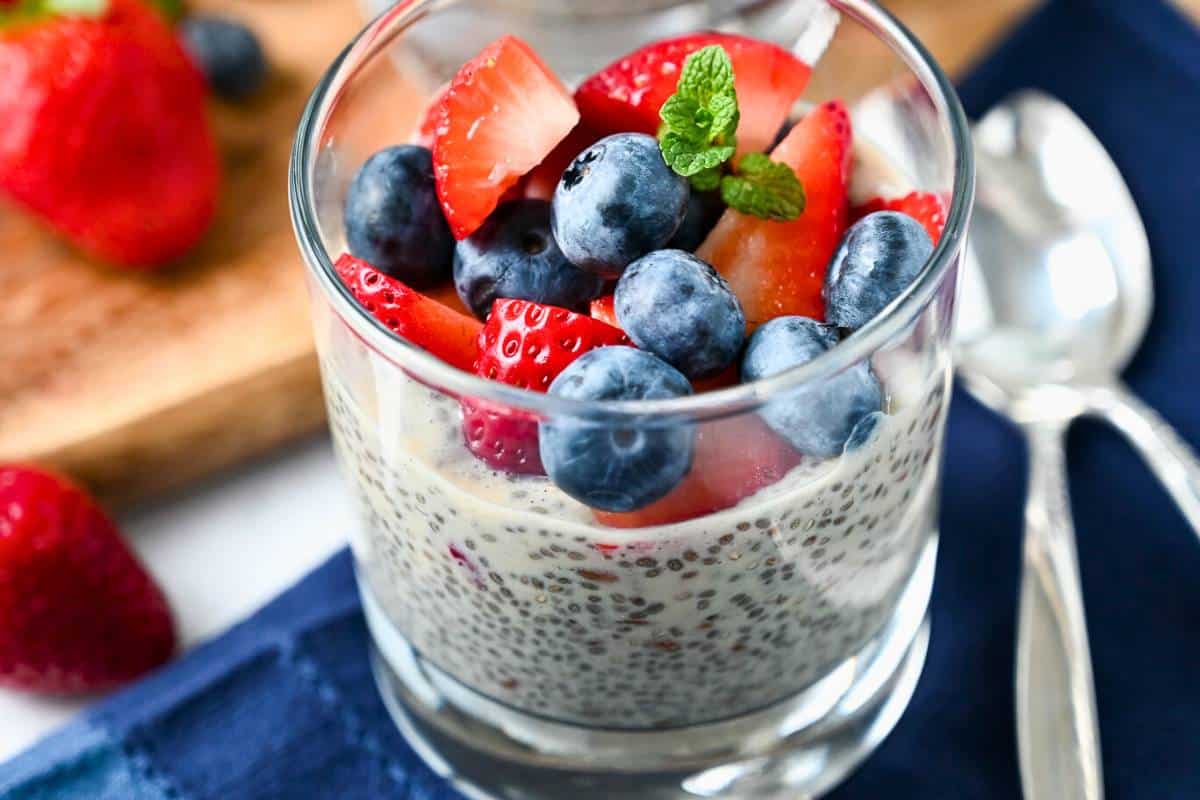 close up of a chia seed pudding with flaxseeds with blueberries and sliced strawberries on top