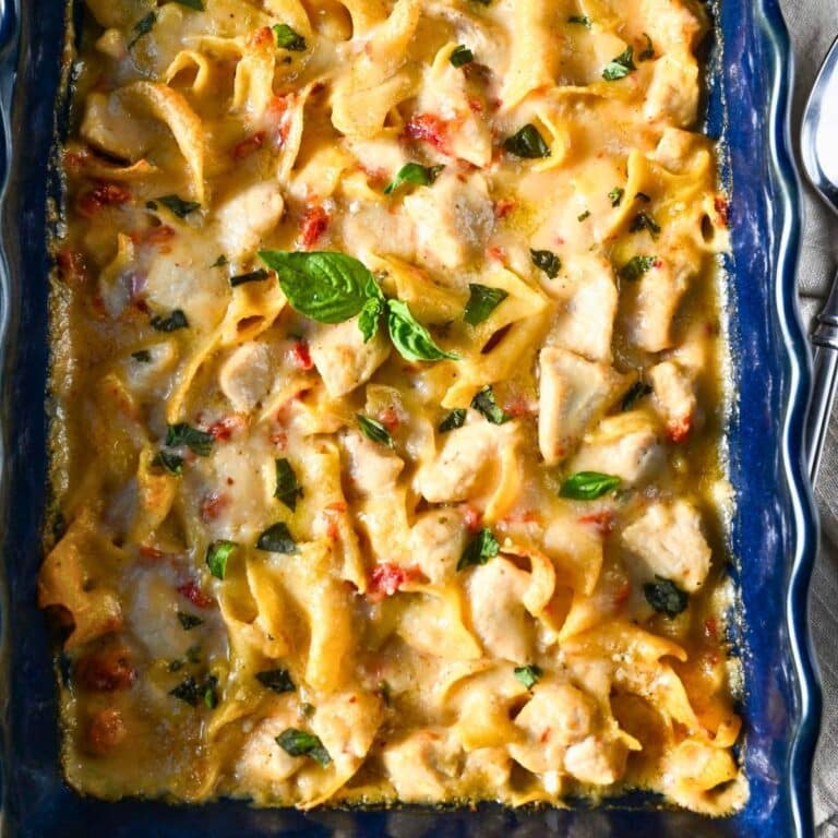 close up of a pan of marry me chicken casserole topped with freshly torn basil