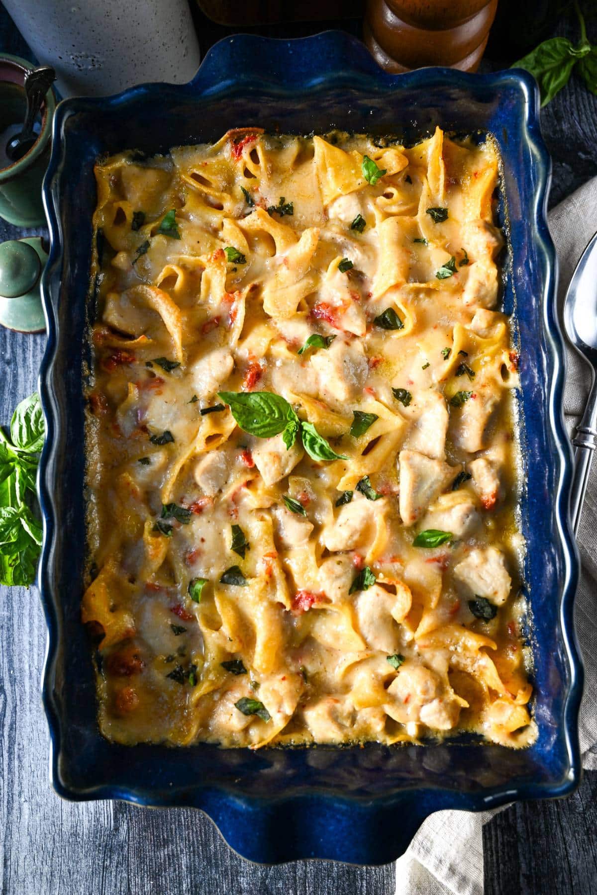 a 9x13 pan of chicken casserole topped with freshly torn basil