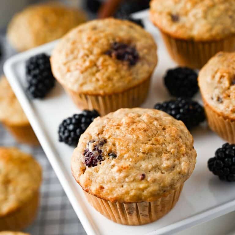 blackberry banana muffins on a white platter with fresh berries