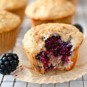 close up of a partially eaten banana blackberry muffin on a cooling rack