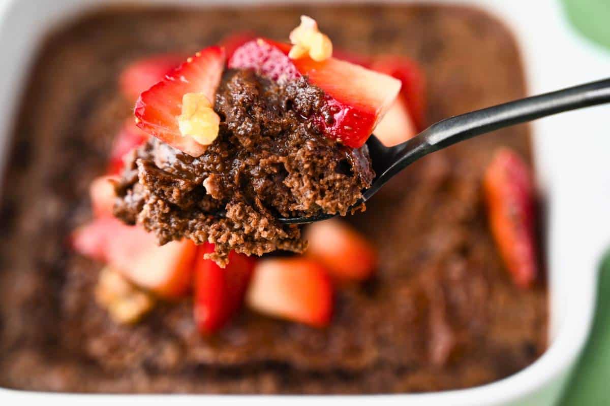 a spoonful of rich chocolate baked oats with strawberries on top