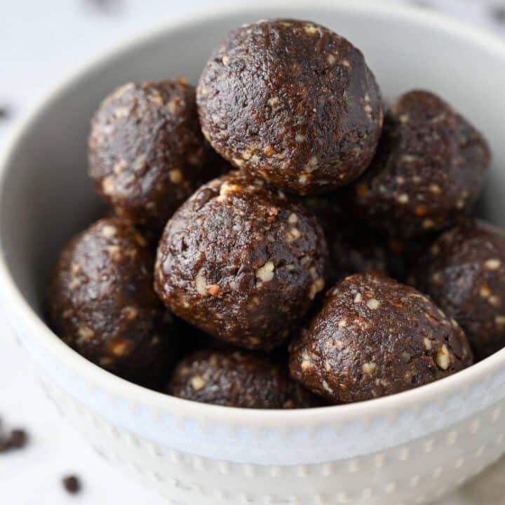 a bowl of brownie protein bites surrounded by mini chocolate chips