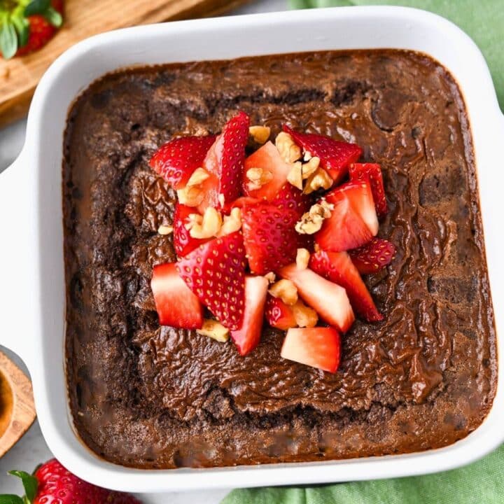 a dish of chocolate baked oats with strawberries and chopped walnuts on top