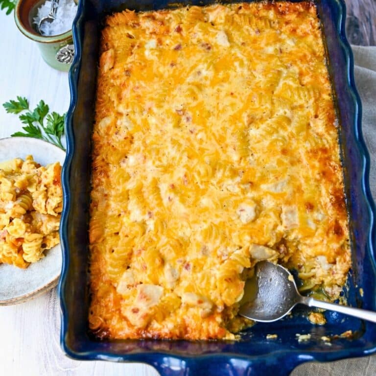a pan of baked mac and cheese with chicken and a served plate with a jar of salt