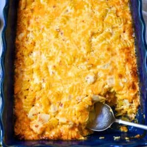 mac and cheese baked up close in the pan with a serving spoon