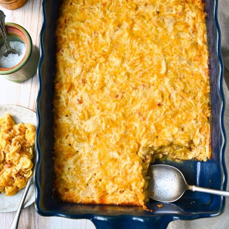 a pan of baked mac and cheese with chicken and a plated serving with a jar of salt