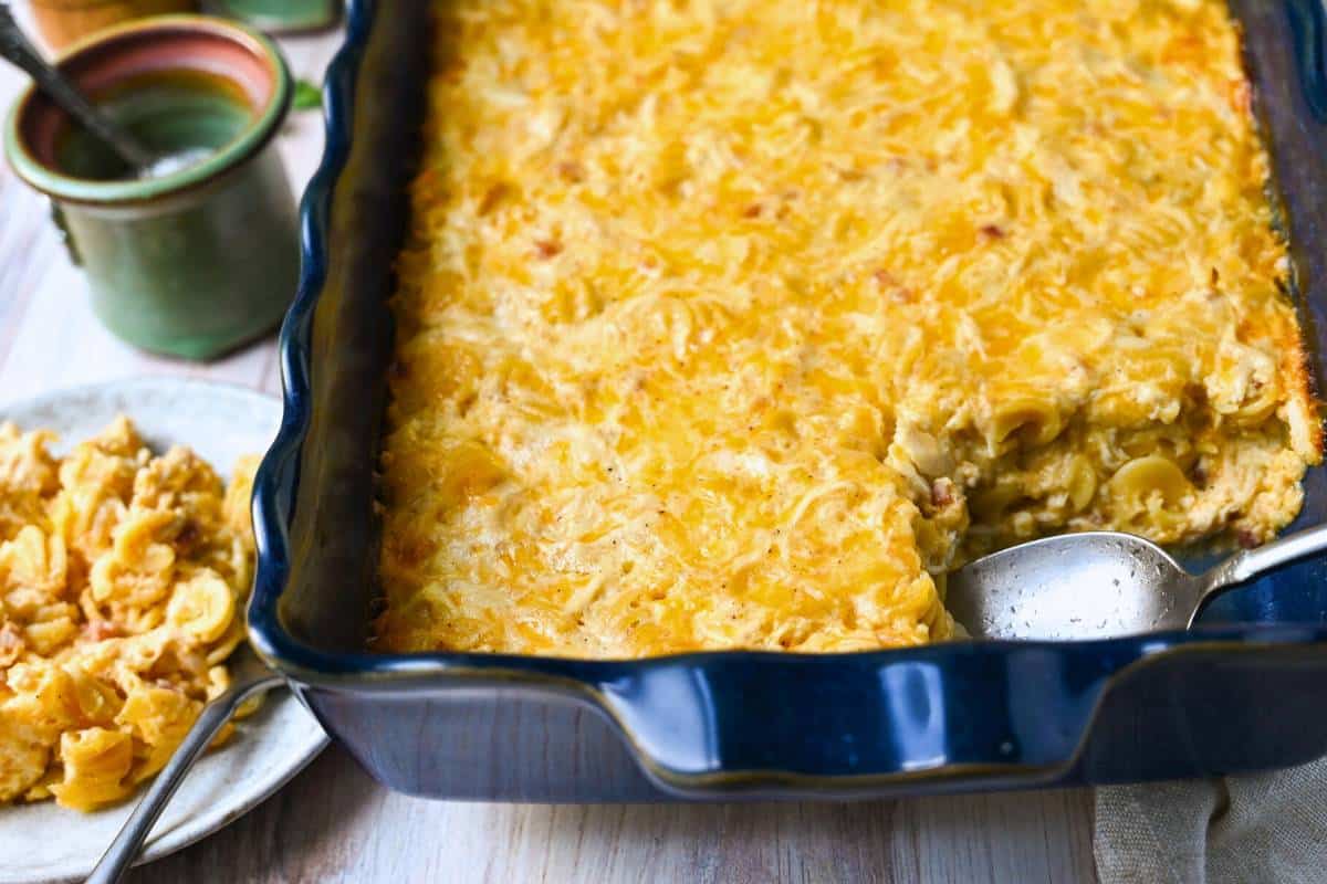 side view of a pan of chicken mac and cheese with a plated serving next to it