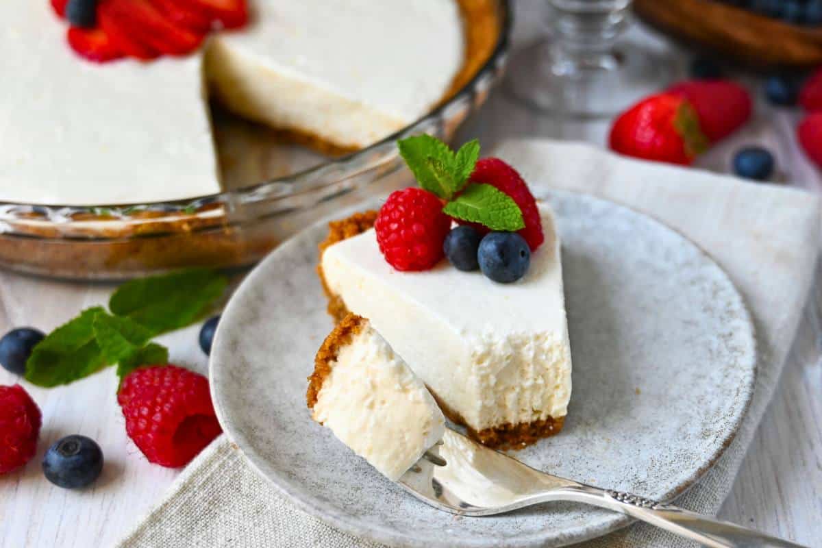 a slice of cheesecake on a plate with a bite cut out of it on a fork