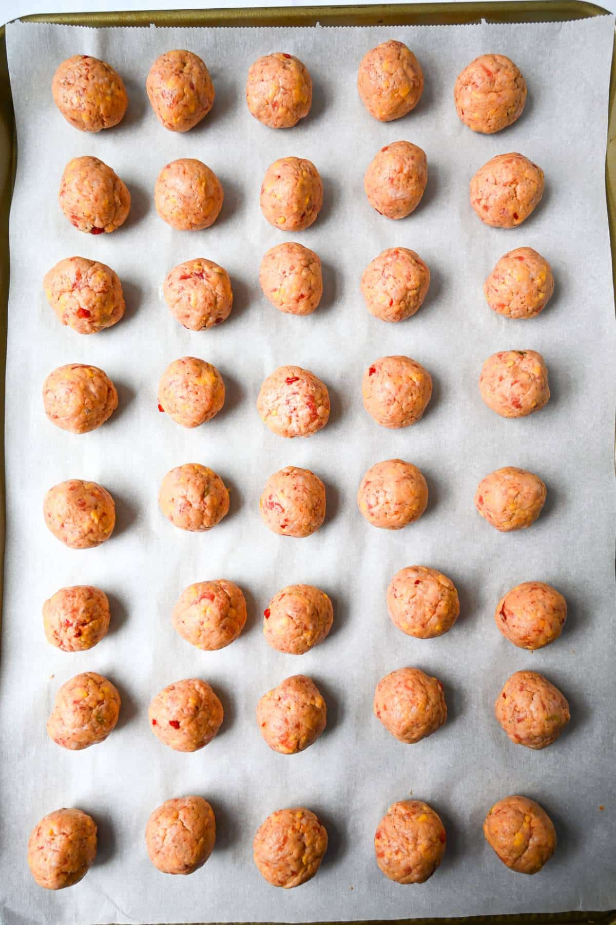 sausage balls ready to bake on a baking sheet lined with parchment
