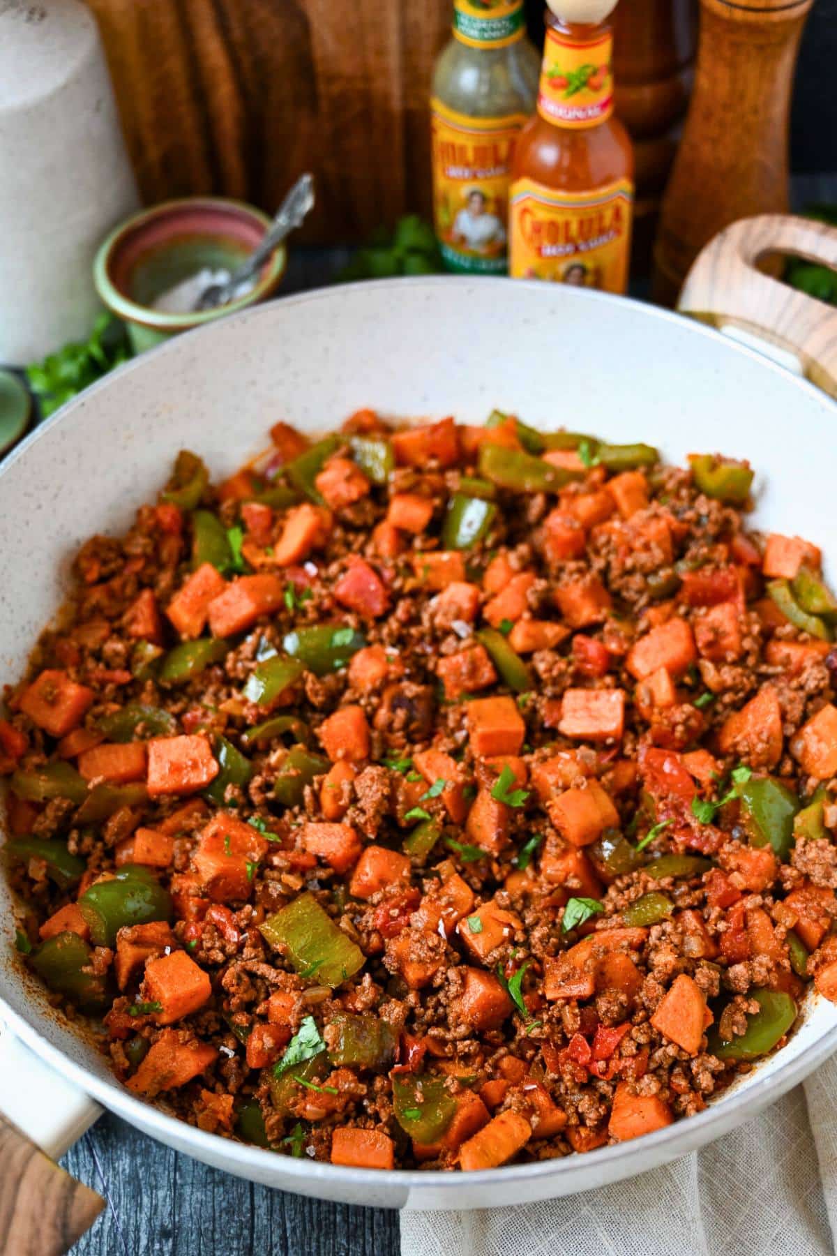 a ground beef skillet with hot sauce and salt on the side
