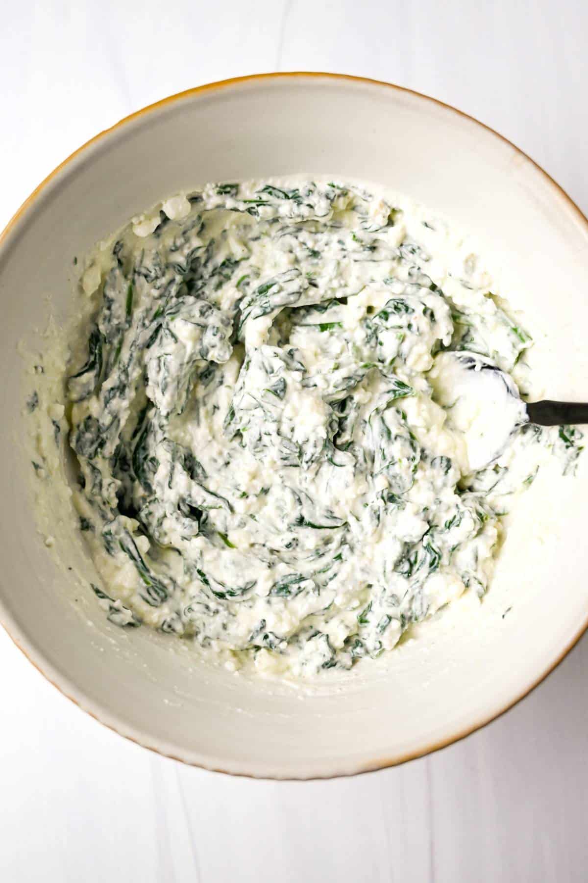 whipped cottage cheese mixed with wilted spinach in a bowl