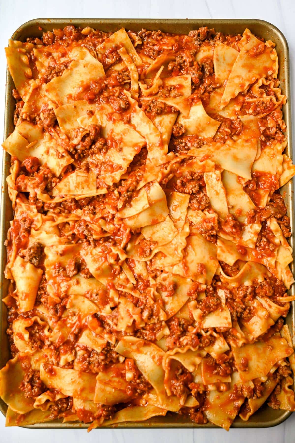 saucy lasanga noodles spread onto a sheet pan