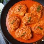 looking down at a skillet of paprika chicken with with a sprig of thyme