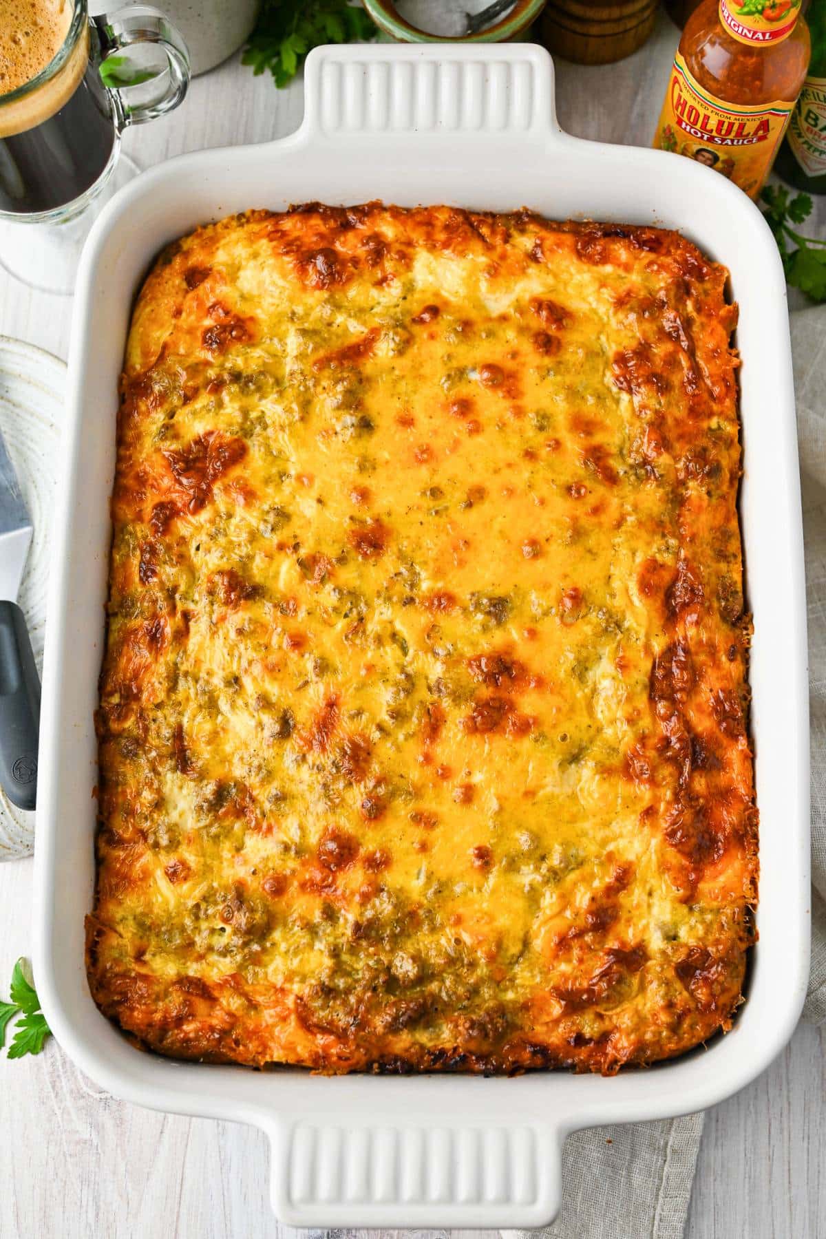 an overhead photo of a baked dish of breakfast casserole made with ground beef, bread cubes, and cheese
