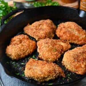 fried chicken in a cast iron skillet with parsley sprinkled on top