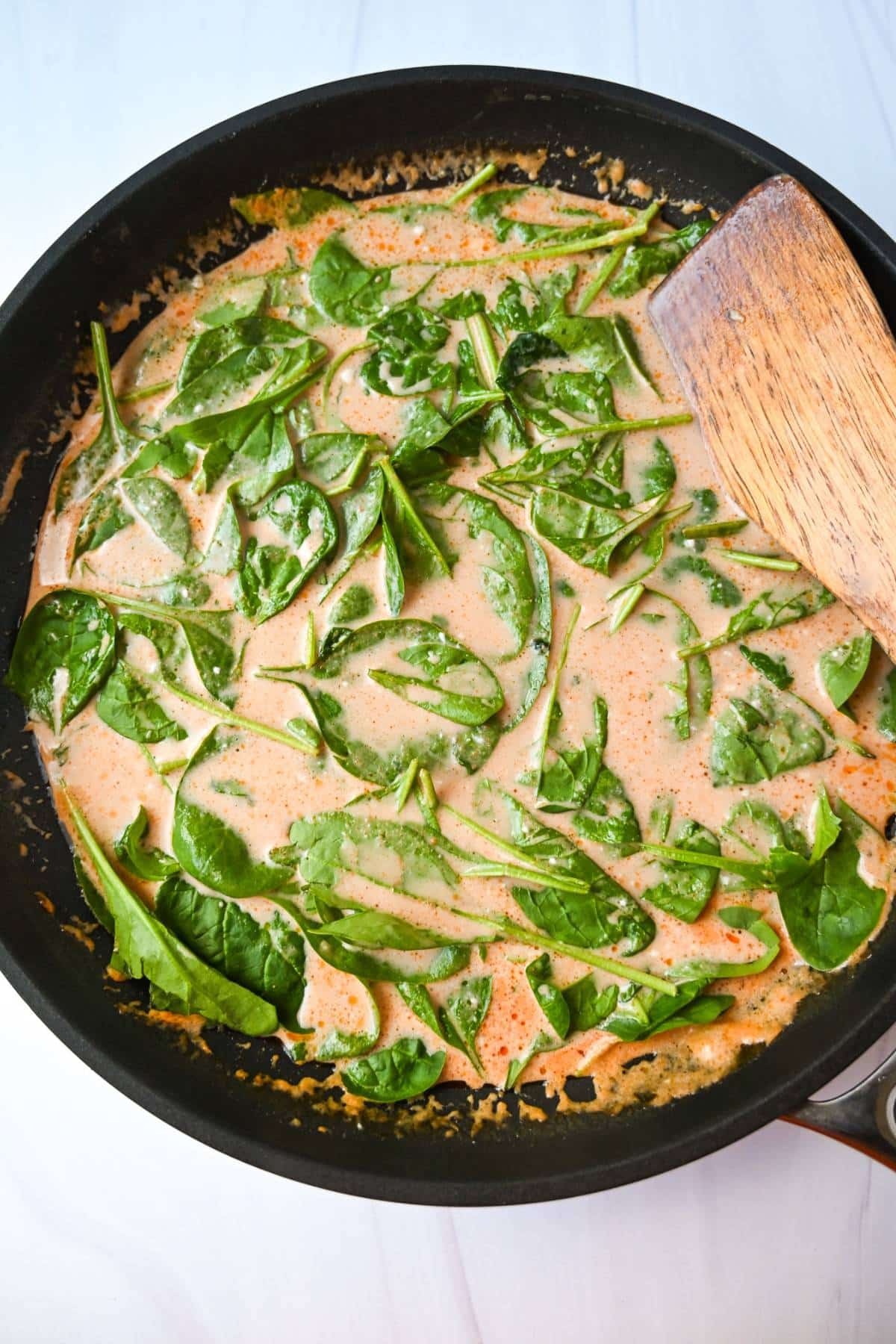 red curry sauce in a skillet with spinach stirred in