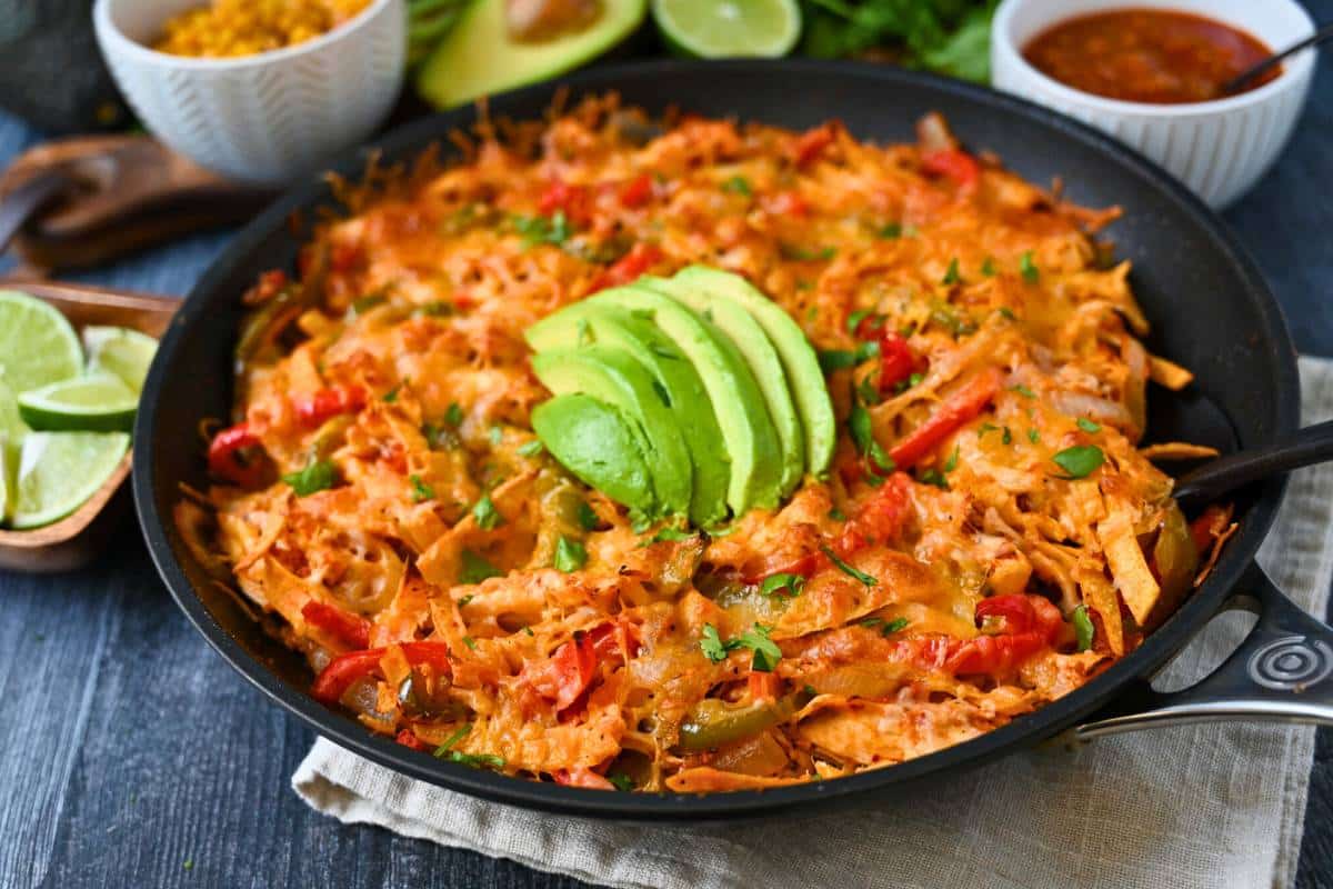 a fajita skillet with chicken, peppers, onions, corn tortillas, and cheese