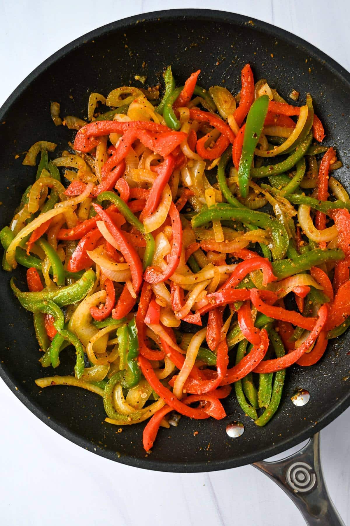 cooked peppers and onions in a skillet