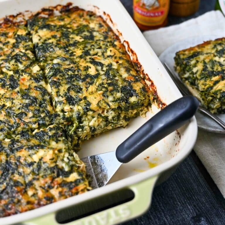a chicken spinach casserole with a spatula and slice cut out