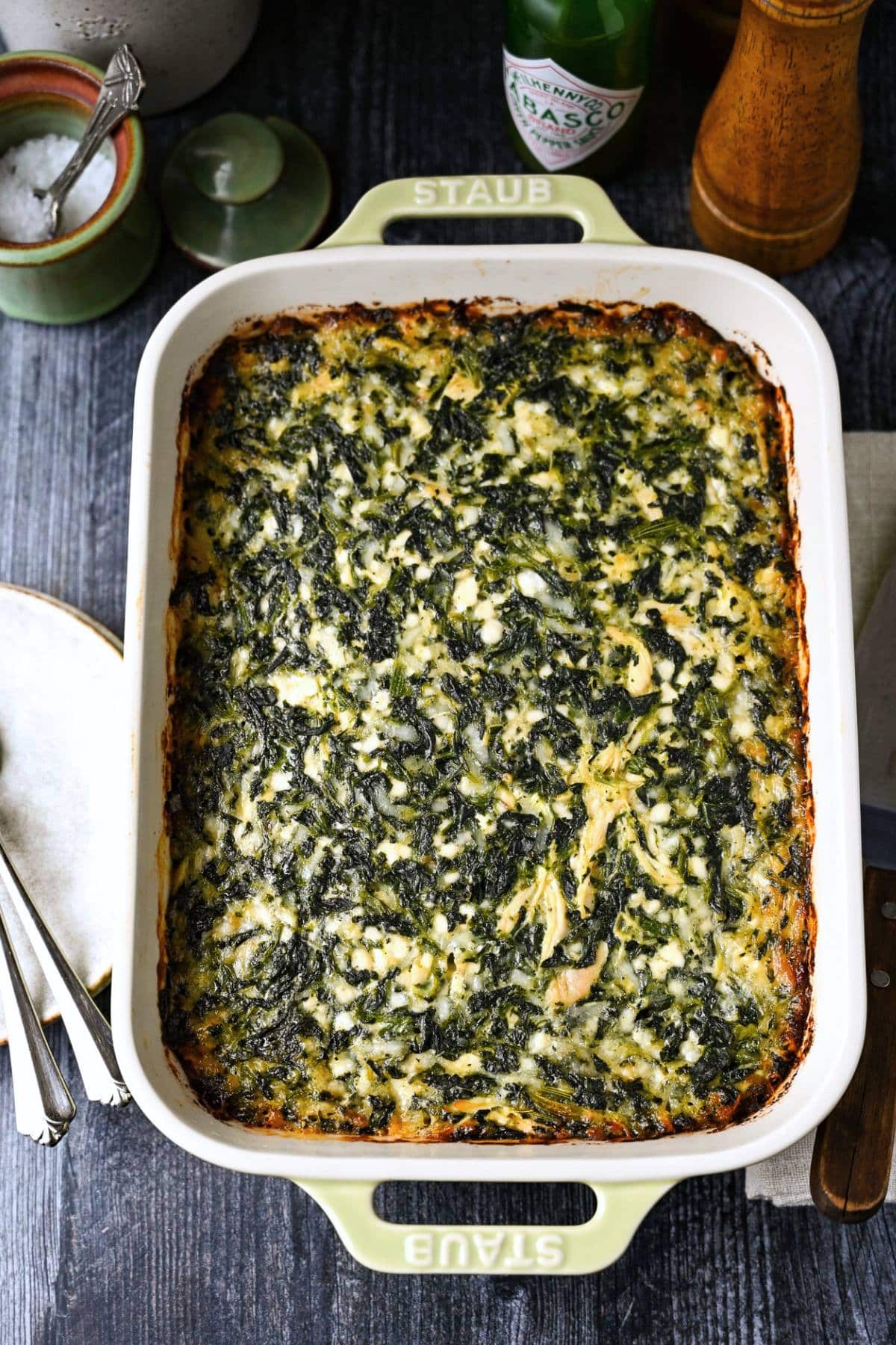 a baked spinach cheese and chicken casserole in a Staub casserole dish