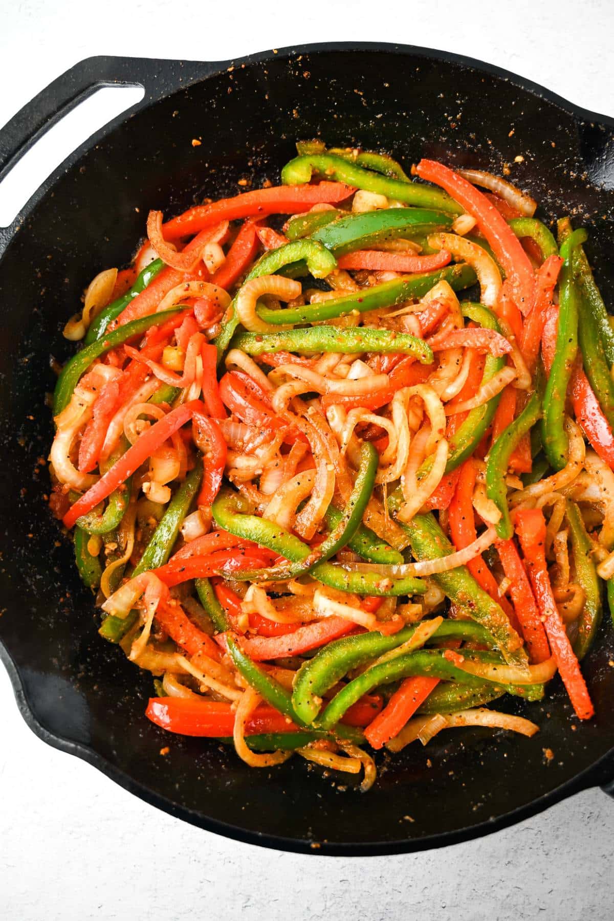 cooked peppers and onions in a cast iron skillet