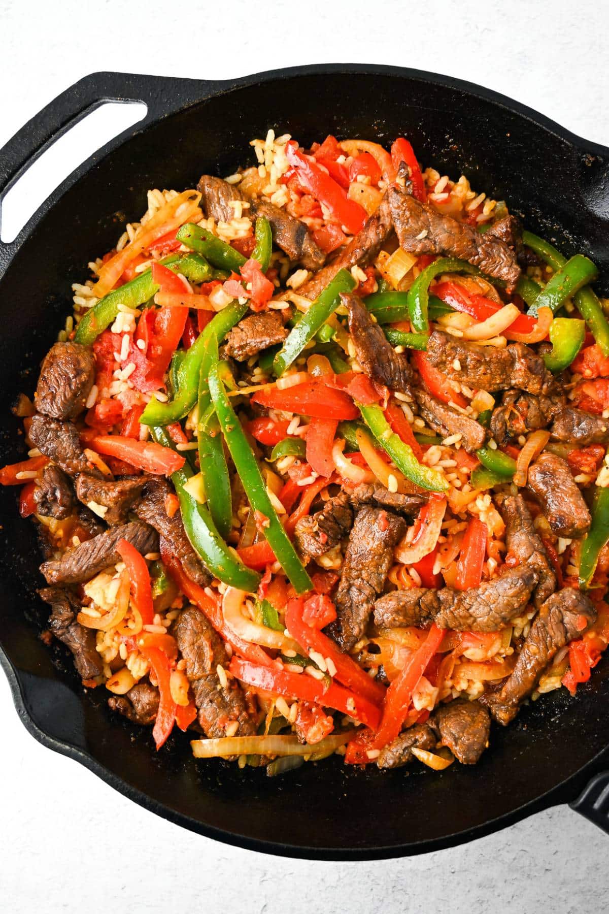 steak fajitas with rice in a cast iron skillet