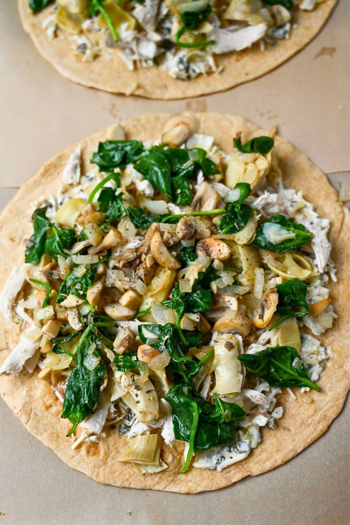 toppings on a tortilla on a parchment lined baking sheet