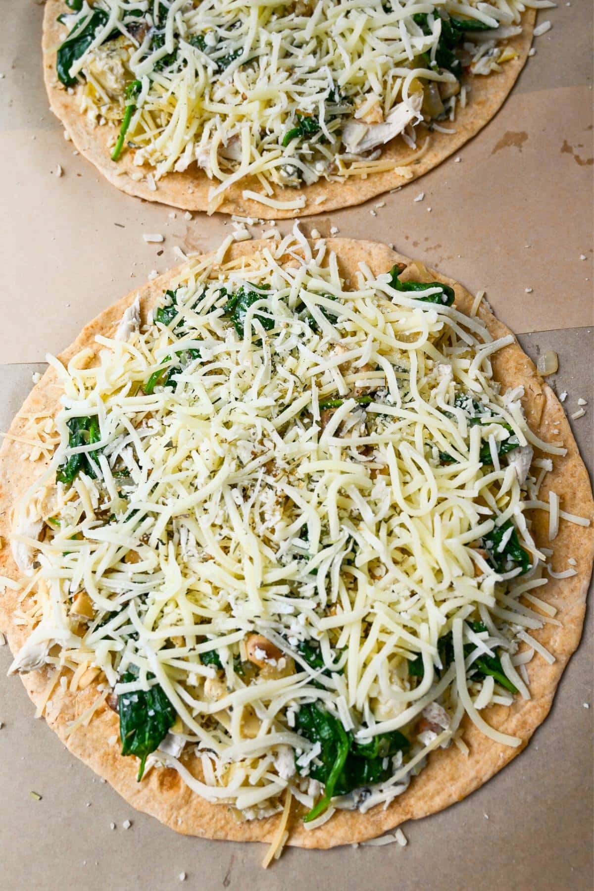 tortilla pizzas topped with toppings and cheese ready to bake