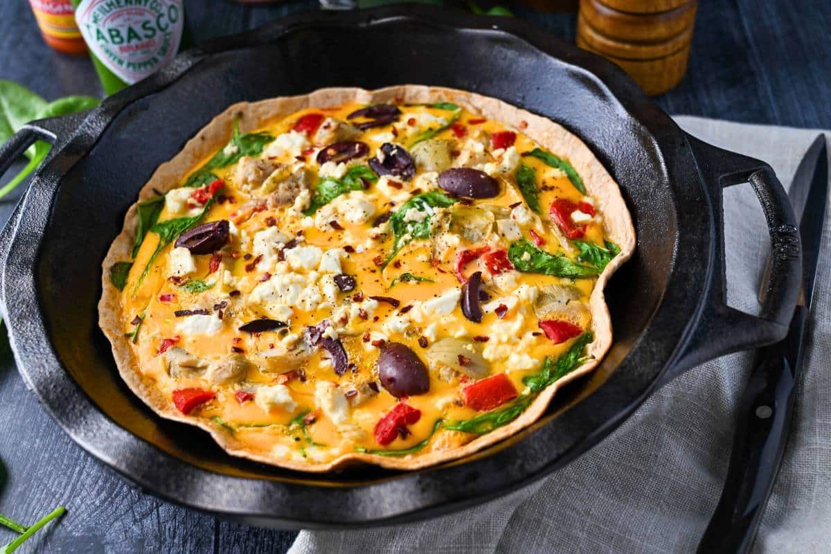 side view of a tortilla egg bake with vegetables in a pie pan