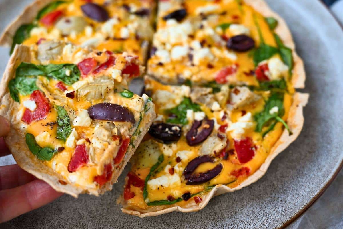 holding up a slice of tortilla egg quiche