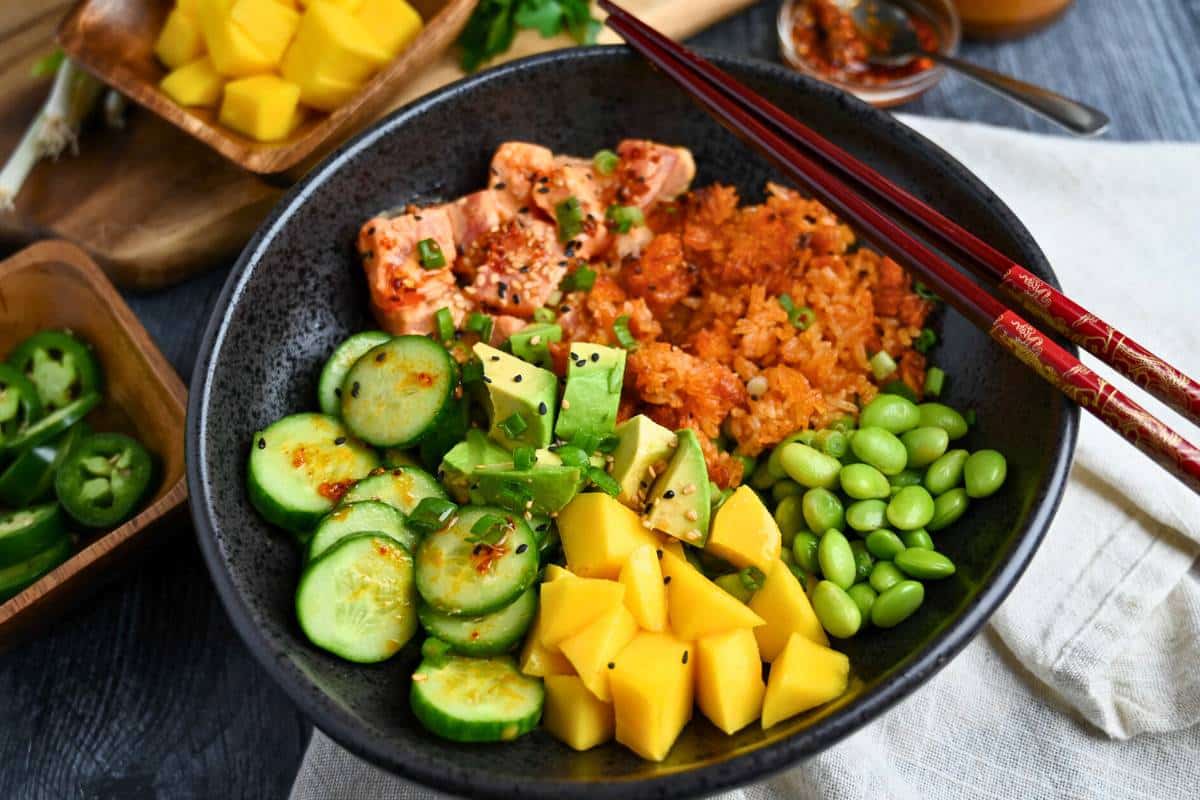 side view of a crispy rice bowl with bowls of toppings