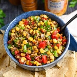 a bowl of bean corn salsa with chips and a spoon