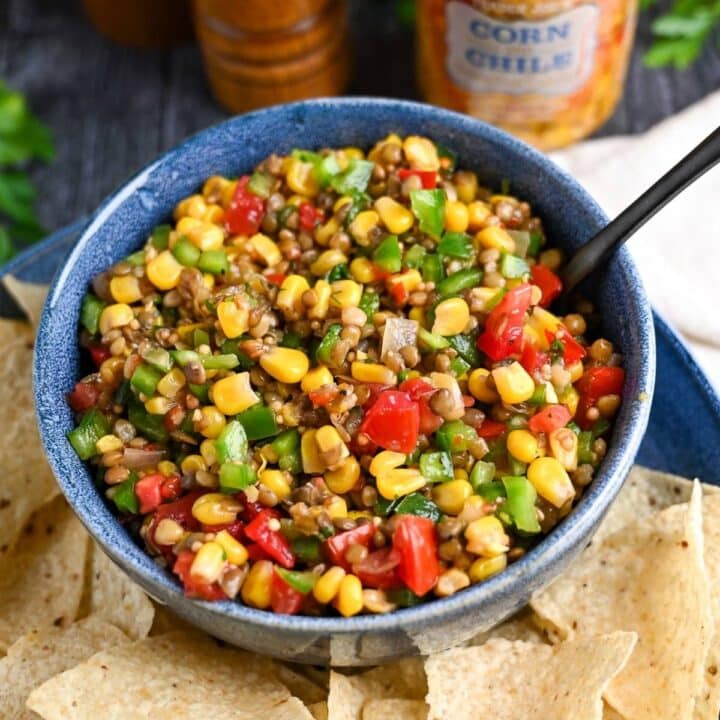a bowl of bean corn salsa with chips and a spoon