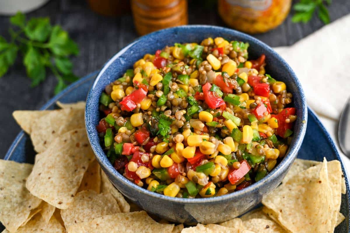 side view of a bowl of lentil salsa with corn and chips