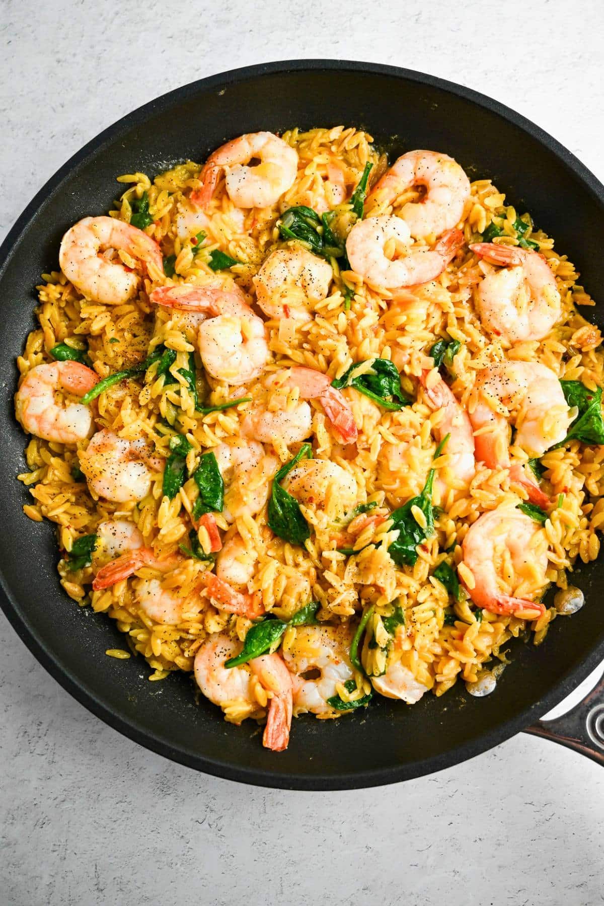 cooked shrimp on top of orzo with baby spinach