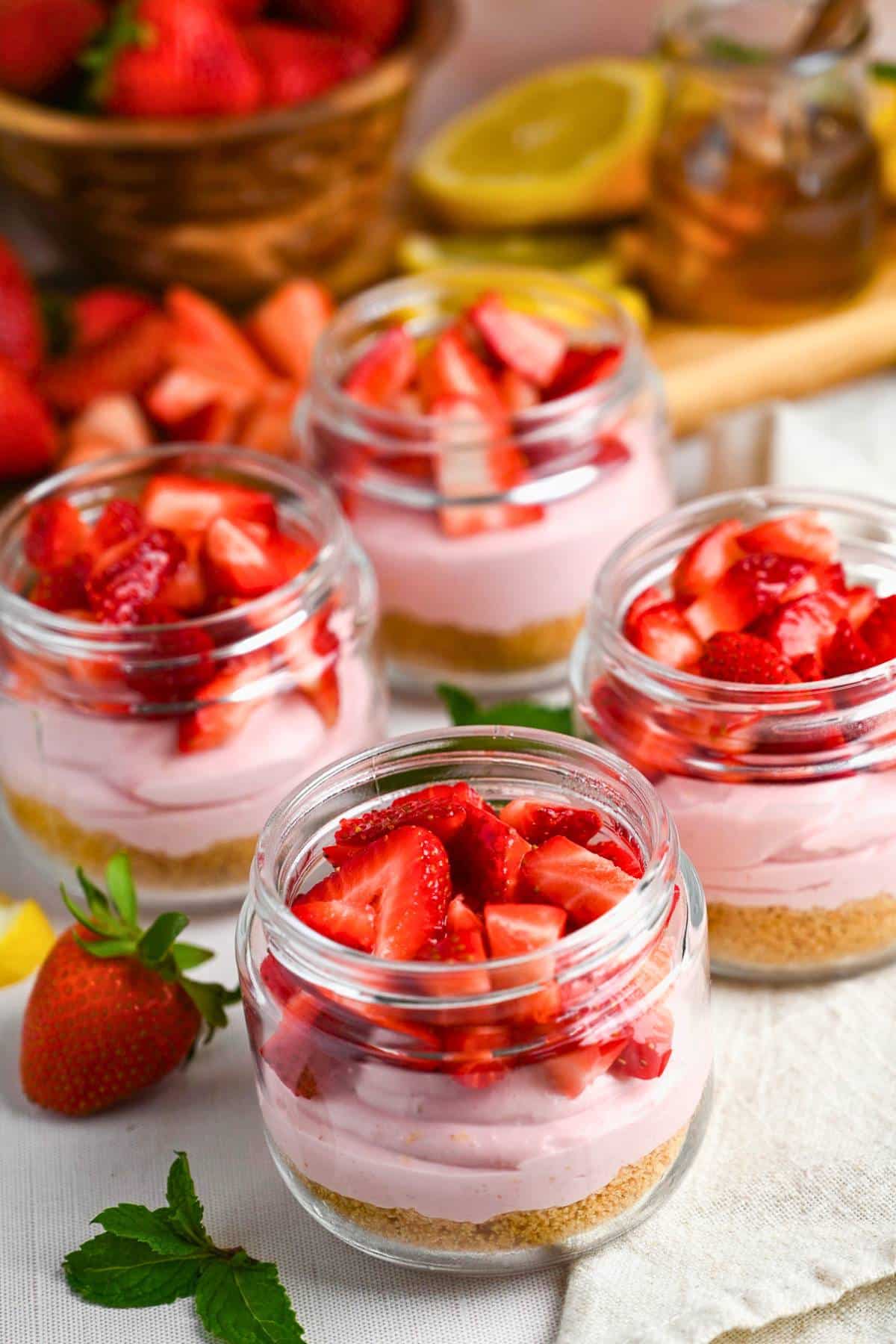 cheesecake parfaits ready to serve with fresh strawberries on top