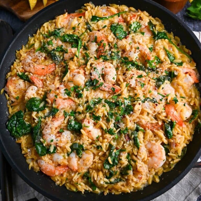 close up of a skillet of shrimp with spinach and orzo pasta