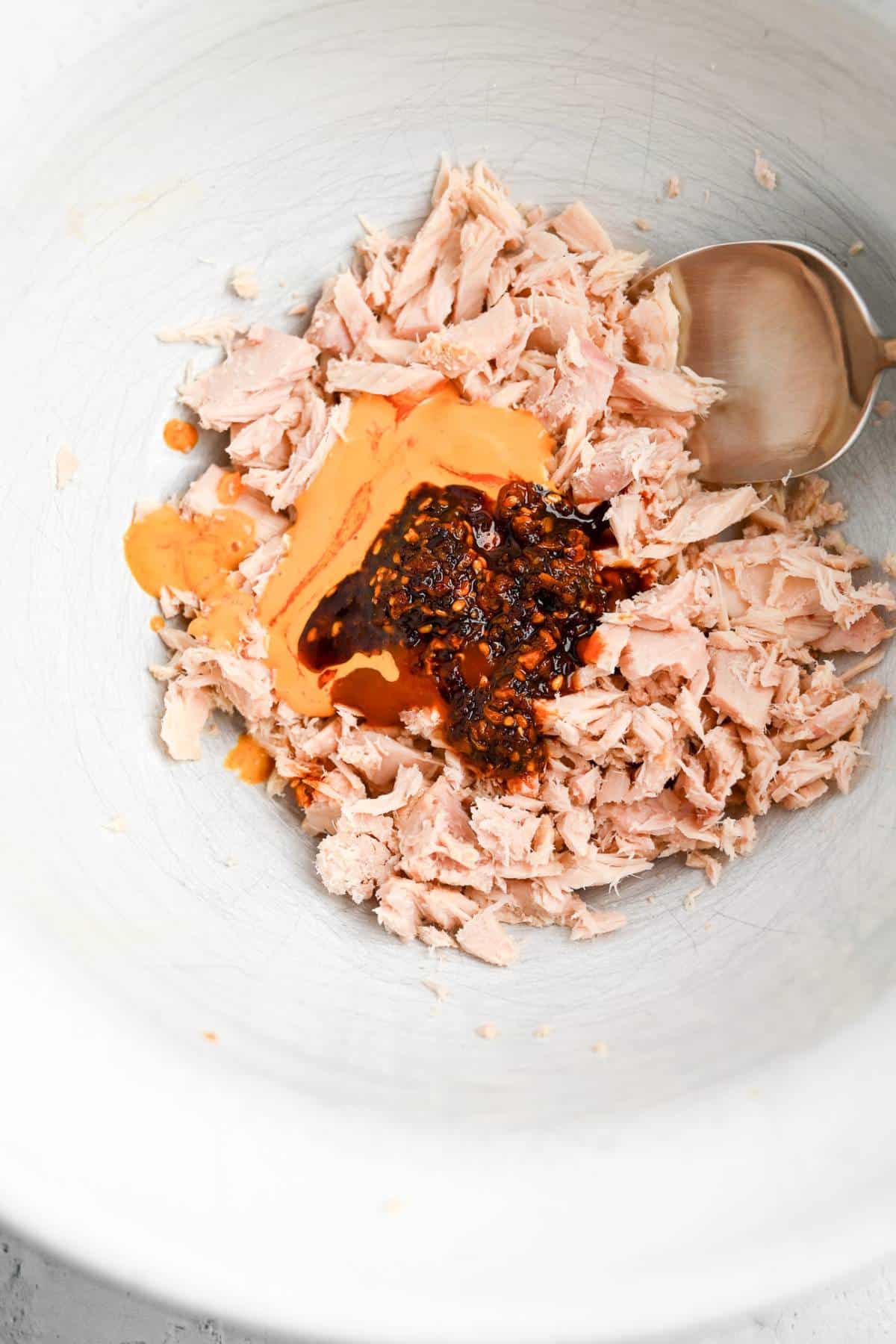 Mixing tuna with sriracha and chili crisp in a bowl