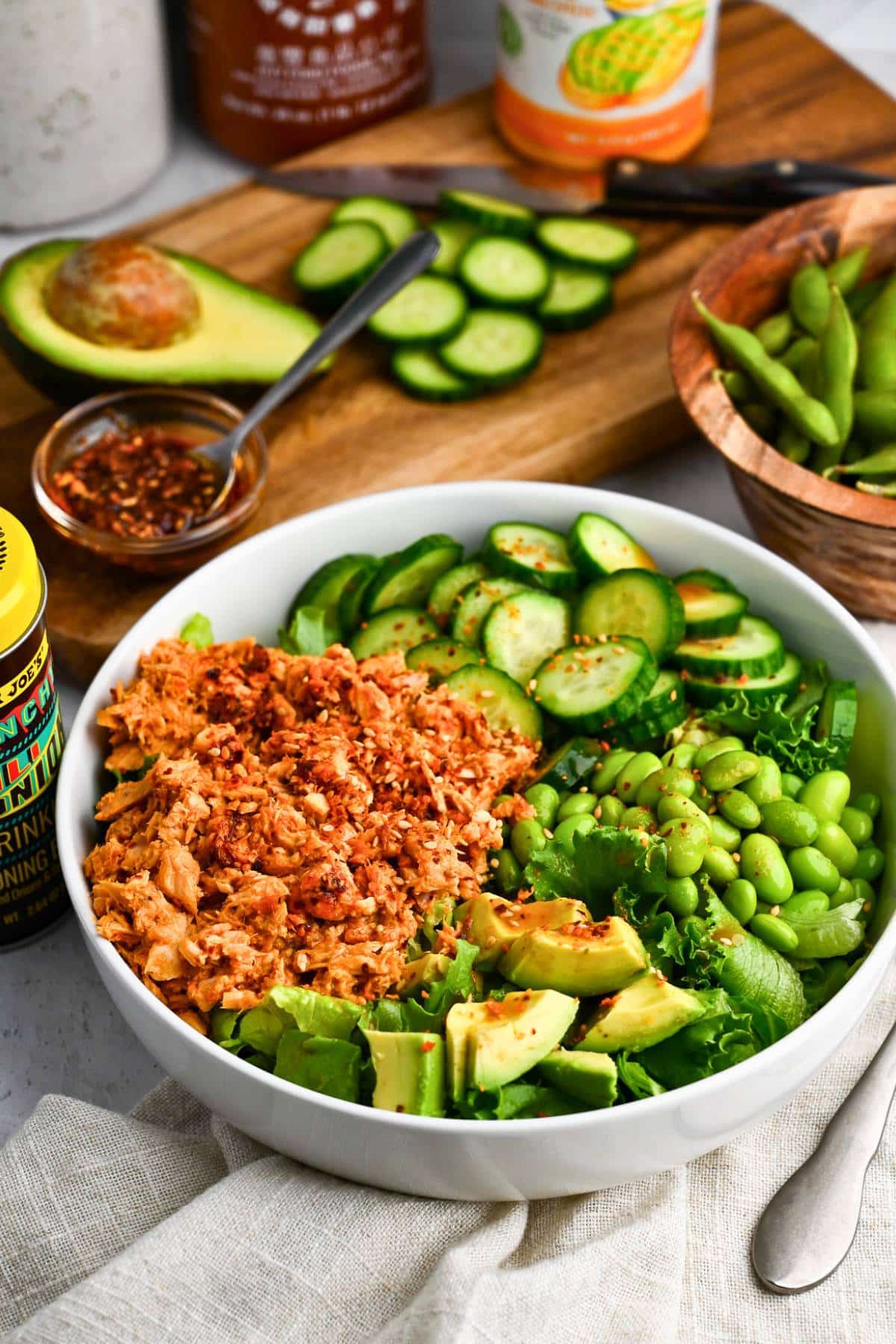sriracha tuna bowl with veggies with chopped veggies in the background 